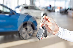 Dealer woman holding keys to a new car. Modern and prestigious vehicles