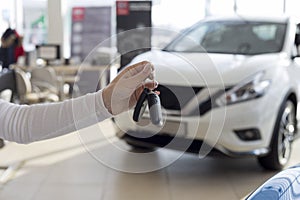 Dealer woman holding keys to a new car. Modern and prestigious vehicles.