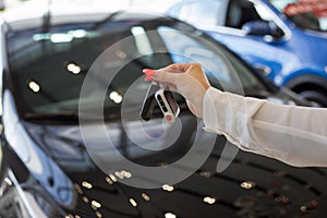 Dealer woman holding keys to a new car. Modern and prestigious vehicles