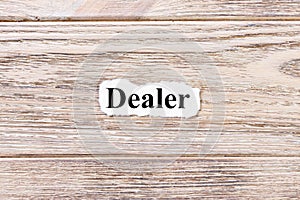 DEALER of the word on paper. concept. Words of DEALER on a wooden background