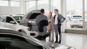 dealership, young man and woman are consulting a car dealership manager on a new auto model in a automobile sales center