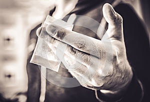 Dealing Illegal Drugs By A Man Holding A Little Bag With White Powder In His Hand In Monochrome Colors