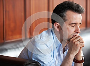 Dealing with a loss. a depressed-looking man sitting on a sofa.