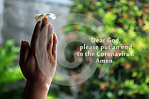 Dear God, please put an end to the Coronavirus. Amen. With young woman clenched hands holding flower in prayer gesture.