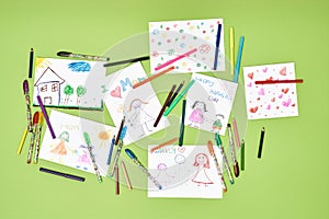 Dear mom, i love you. Top view of colorful child drawings for mothers day and felt tip pens lying on green table