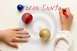 Dear Santa - wish card written by kid to Santa Claus at Christmas. Child`s hands writing letter with a red felt pen