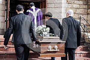 Death, funeral and holding coffin in church for grief, bereavement and with family together on steps. Grieving, sad and photo