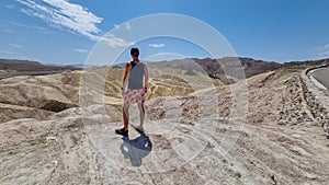 Death Valley - Man with scenic view Badlands of Zabriskie Point, Furnace creek, Death Valley National Park, California