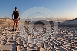 Death Valley - Man standing on dry cracked clay crust at Mesquite Flat Sand Dunes in Death Valley National Park, California, USA