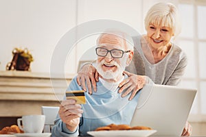 Loving couple of pensioners checking their debit card number