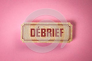 DEBRIEF. Text in French on a cardboard sticker