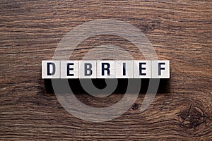 Debrief - word concept on building blocks, text