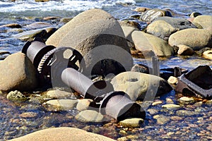 Debris from old shipwreck scattered amongst large rocks along the coast of Gros Morne