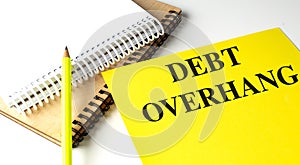 DEBT OVERHANG text on yellow paper with notebooks photo