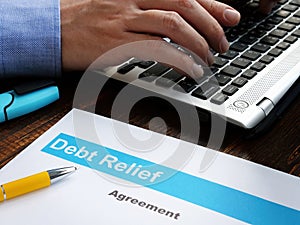 Debt relief agreement papers and man with laptop.