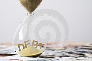 Debt wording inside of hourglass on banknote for countdown payment money demo debtor to creditor concept, economic recession and