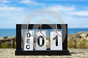 Dec 01 calendar date text on wooden frame with blurred background of ocean