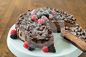 A decadent Chocolate Mousse Cake with chocolate ganache and topped with Raspberries, Blackberries and chocolate curls