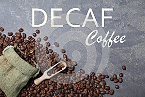 Decaf coffee beans, bag and wooden scoop on grey table, flat lay