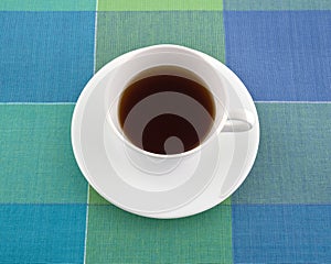 Decaffeinated black tea in a cup on a place mat.