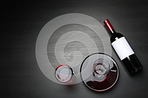 Decanter, glass and bottle with red wine on dark background, flat lay.