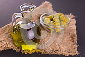 Decanter with olive oil and olives in a bowl. Close-up.