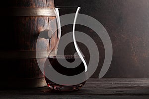 Decanter with red wine and old wooden barrel