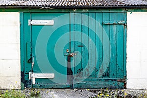Decaying locked wooden green garage doors