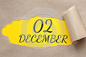 december 02. 02th day of the month, calendar date.Hole in paper with edges torn off. Yellow background is visible