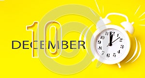 December 10th. Day 10 of month, Calendar date. White alarm clock with calendar day on yellow background. Minimalistic concept of