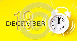 December 18th. Day 18 of month, Calendar date. White alarm clock with calendar day on yellow background. Minimalistic concept of