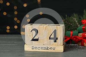 December 24 - Christmas Eve. Wooden block calendar and decor on table against blurred festive lights