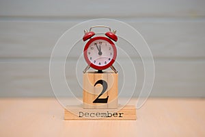 December 2nd set on wooden calendar and red alarm clock with blue background