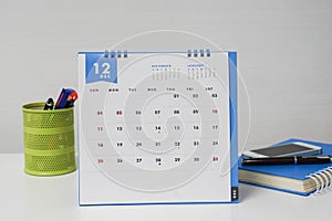 December calendar with stationary box and notebook on businesswoman desk