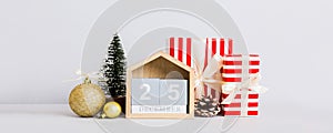 25 december. Christmas composition on colored background with a wooden calendar, with a gift box, toys, bauble copy photo