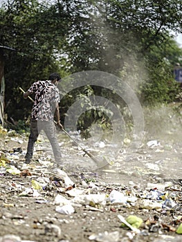 December, 2022, Raipur, India: Man sweeping the trash with broom and polyhthene big garbage area, Man cleaning the polluted area,
