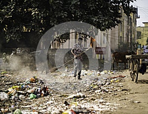 December, 2022, Raipur, India: Man sweeping the trash with broom and polyhthene big garbage area, Man cleaning the polluted area,