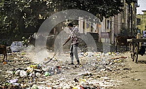 December, 2022, Raipur, India: Man sweeping the trash with broom and polyhthene big garbage area, Man cleaning the polluted area,