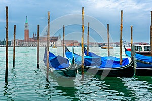 December 2, 2021 - Venice, Italy: Gondolas moored at Sam Marco Gondola Service Station on Grand Canal with Chiesa di San Giorgio M photo