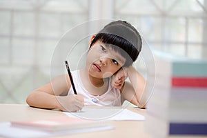 Decent school child. holding her head with a hand and reading a book