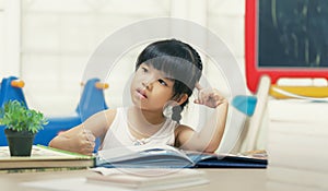 Decent school child. holding her head with a hand and reading a book