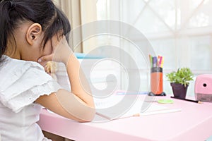 Decent school child. holding her head with a hand and reading a book