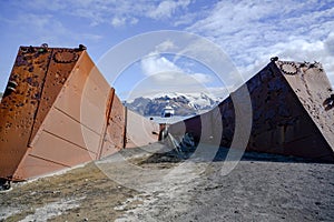 Deception Island, Antarctica. Sunken tanks of abandoned whale station with cruise liner in background. Lost places.