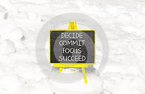 Decide commit focus succeed symbol. Concept word Decide Commit Focus Succeed on beautiful blackboard. Beautiful white snow