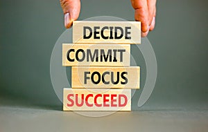 Decide commit focus succeed symbol. Concept word Decide Commit Focus Succeed on wooden block. Beautiful grey background.