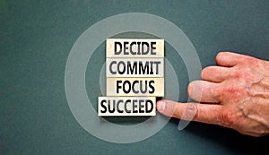 Decide commit focus succeed symbol. Concept word Decide Commit Focus Succeed on wooden block. Beautiful grey background.