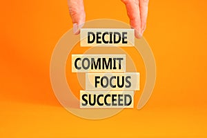 Decide commit focus succeed symbol. Concept word Decide Commit Focus Succeed on wooden block. Beautiful orange background.