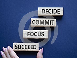 Decide Commit Focus Succeed symbol. Concept words Decide Commit Focus Succeed on wooden blocks. Businessman hand. Beautiful deep