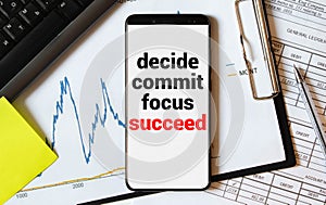 Decide, commit, focus, succeed. Words on notepad with eyeglasses, coffee, keyboard