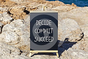 Decide commit succeed symbol. Concept word Decide Commit Succeed on beautiful black chalk blackboard. Beautiful stone beach sea